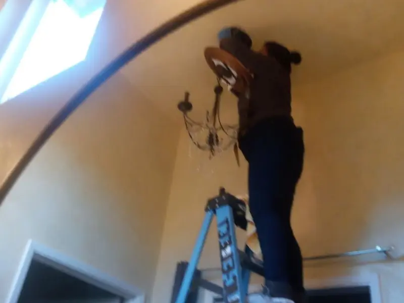 Electrician installing a chandelier in a Independence residence